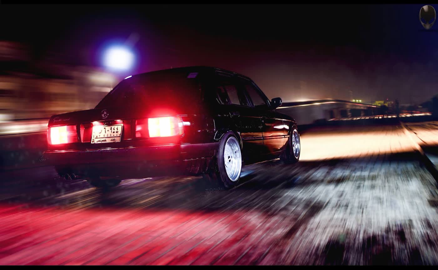 BMW E30 panning at night on wet asphalt